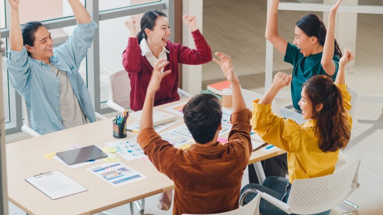 Group of young creative people discussing business gesture hand high five at office.