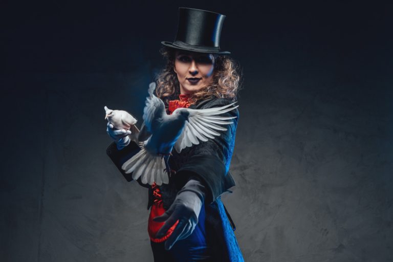 Serious female magician with white pigeons and top hat in dark background