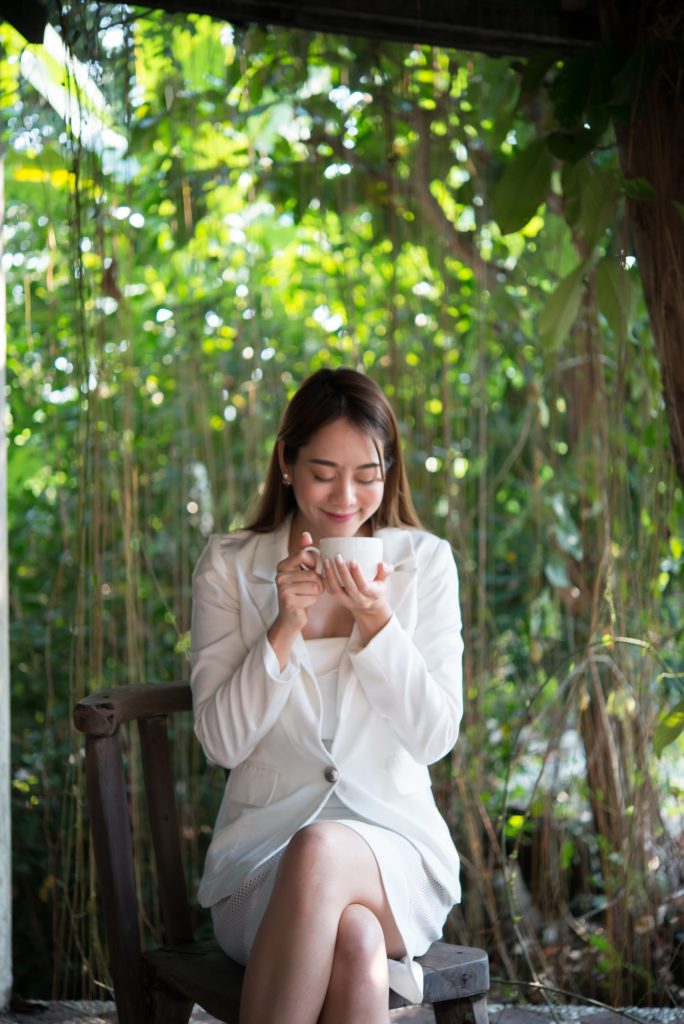 Young woman looking away with happy smile, glad for good weather,relaxing with coffee before work.