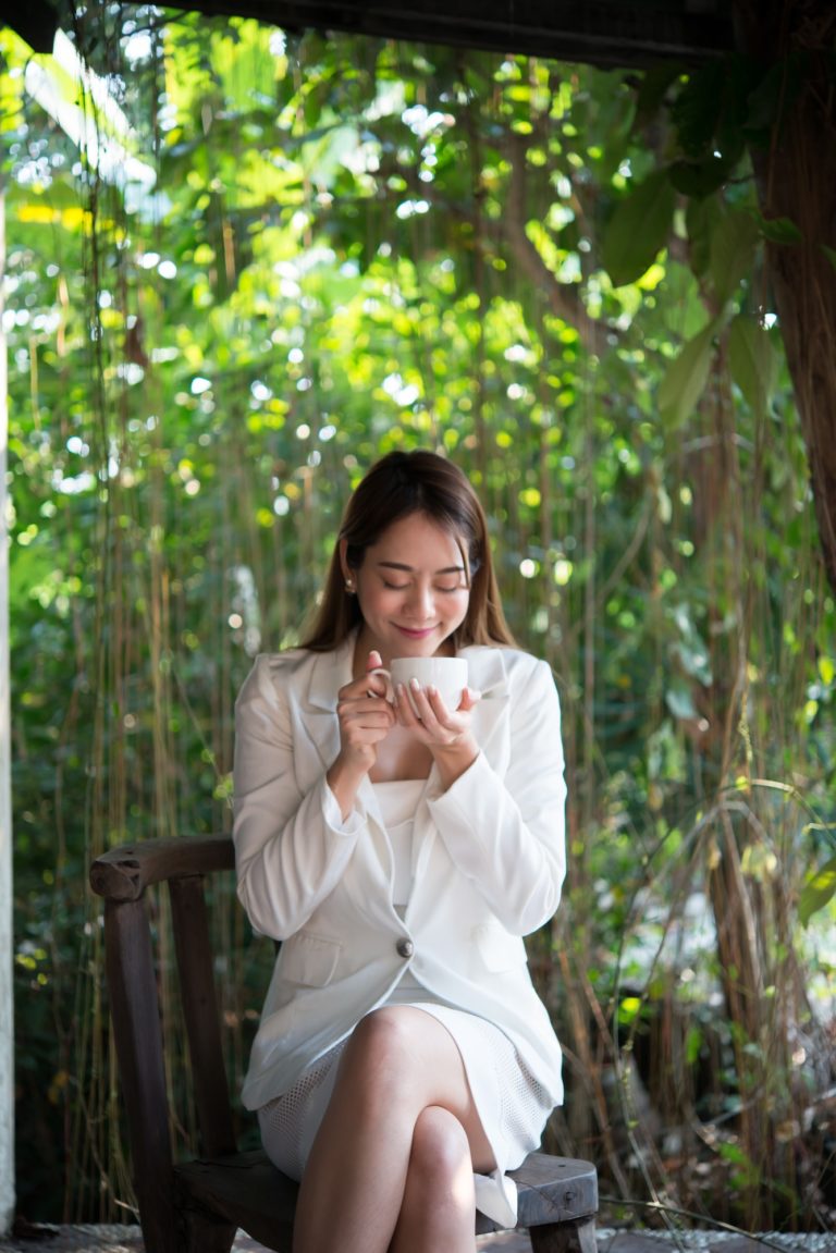 Young woman looking away with happy smile, glad for good weather,relaxing with coffee before work.