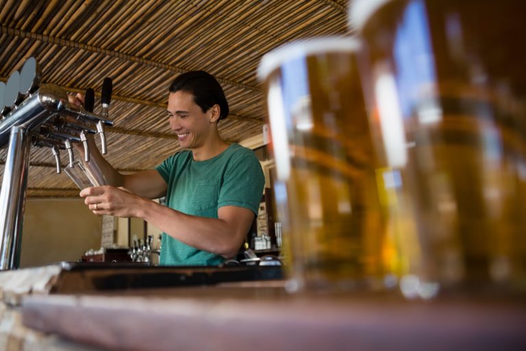 Close-up of beer glasses with bartender working at restaurant