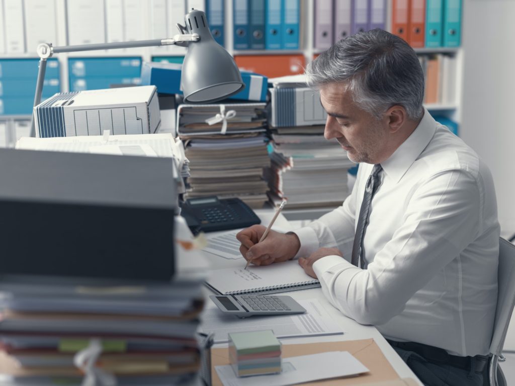 Businessman working in the office and piles of paperwork
