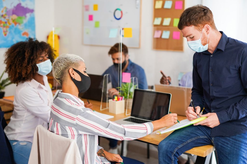 Multiracial people in coworking office with safety measures for coronavirus